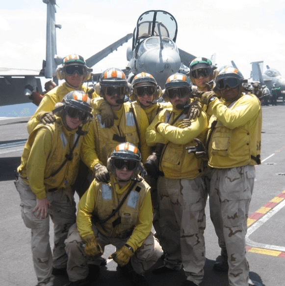 Bill standing on a navy flight deck, reinforcing the summit's leadership and transition context.